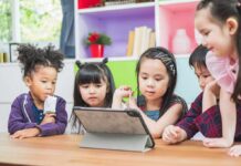 Children gathered around a tablet on a table