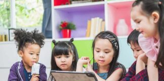 Children gathered around a tablet on a table