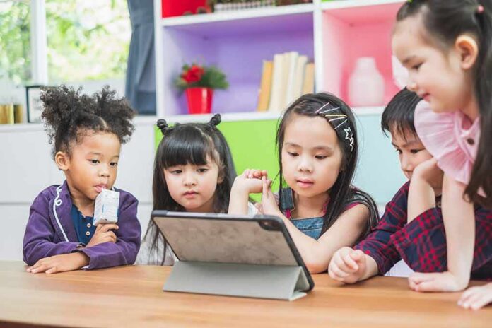 shutterstock_1407865199 Children gathered around a tablet on a table