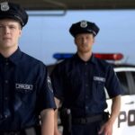 Two police officers standing near a patrol car