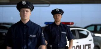 Two police officers standing near a patrol car