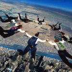 She Fell 10,000 Feet Unconscious—and Lived Skydivers forming a circle in freefall over a city and farmland