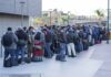 Fernando Salas and a large group of travelers waiting in a long line with luggage