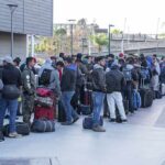 Fernando Salas and a large group of travelers waiting in a long line with luggage