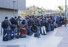 Fernando Salas and a large group of travelers waiting in a long line with luggage