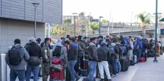 Fernando Salas and a large group of travelers waiting in a long line with luggage