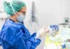 medical professional in blue gown putting on sterile gloves