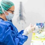 medical professional in blue gown putting on sterile gloves