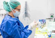 Birthright Twist Fuels Surrogacy Boom medical professional in blue gown putting on sterile gloves
