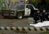 Crime scene with police car and two investigators by a covered body