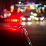 Police car with flashing red lights on a city street at night