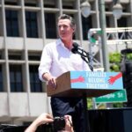 Man speaking at a rally podium outdoors