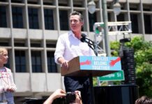 Man speaking at a rally podium outdoors