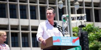 Man speaking at a rally podium outdoors