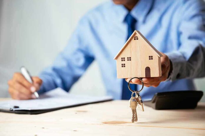 Hand holding a wooden house model with keys