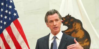 Gavin Newsom speaks at a podium with U.S. and California flags behind him