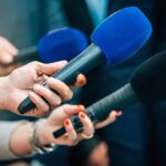 Ring Light Stops Match — Umpire Steps In Reporters holding colorful microphones
