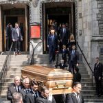 Second Hit Fells Student Hero Pallbearers carry a casket down church steps