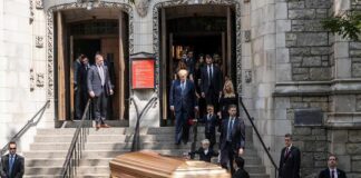 Pallbearers carry a casket down church steps