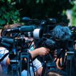 Savage Takedown Sparks Embassy Chaos TV news cameras crowding together at an outdoor event