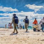 Beach patrol officers walking among beachgoers on a sunny shoreline