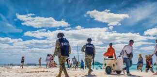 Beach patrol officers walking among beachgoers on a sunny shoreline