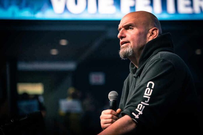 Bald man in a hoodie speaking into a microphone on stage