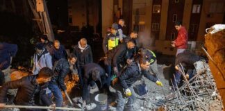 Rescue workers dig through rubble at night