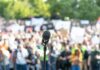 Microphone on a stand facing a large blurred crowd