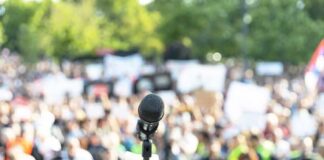 Microphone on a stand facing a large blurred crowd