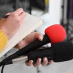 Missile Rehearsal Eyes American Carriers Journalist holding two microphones while writing in a notebook