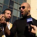 Two men speaking to reporters with microphones outside a modern building