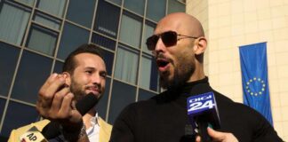 Two men speaking to reporters with microphones outside a modern building