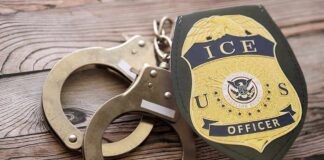 ICE officer badge and handcuffs on wooden surface
