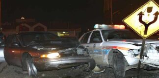 A damaged car and a police vehicle involved in a nighttime accident