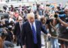 Donald Trump walks up steps through a crowd as A. J. Calloway films nearby