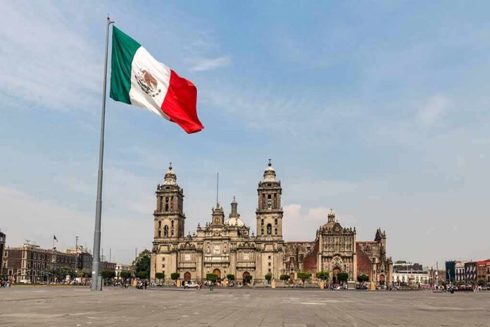 Mexican flag flying over a historic cathedral in a large plaza