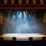 Empty theater stage with spotlights and red curtains