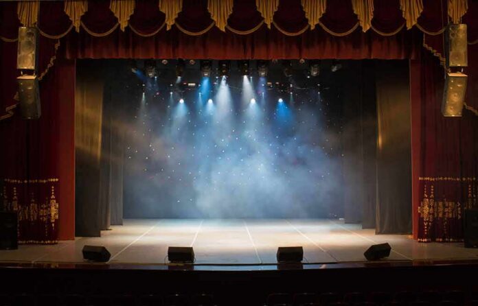 Empty theater stage with spotlights and red curtains