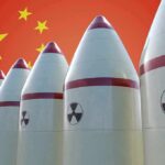 Row of nuclear missiles with radiation symbols before a red flag with yellow stars