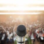 Microphone on stage facing a blurred audience