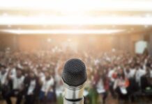 Microphone on stage facing a blurred audience