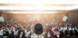 Microphone on stage facing a blurred audience