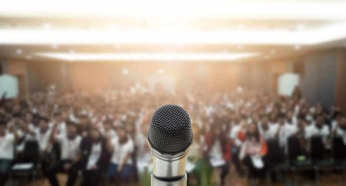 Microphone on stage facing a blurred audience