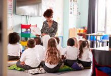 Teacher reading a book to a group of young students on the classroom floor