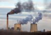 Industrial power plant with smokestack and cooling towers emitting smoke