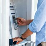 $128K Temptation – One Call Changed Everything Person using an ATM with a bank card