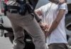 police officer handcuffing a person beside a vehicle