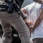 Priority Cartel Target Captured in Ciudad Juárez police officer handcuffing a person beside a vehicle