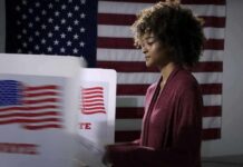 Voter at a polling booth with an American flag backdrop